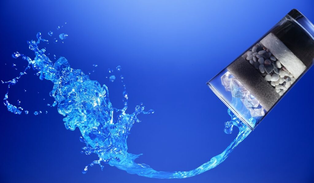 Proces filtracji wody – warstwowy filtr z węglem aktywnym, piaskiem i kamieniami przepuszczający krystalicznie czystą wodę, symbol skutecznego uzdatniania wody w domu.